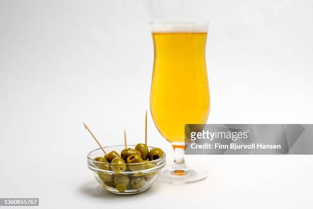 green olives and a glass of beer. isolated against a white background - finn bjurvoll imagens e fotografias de stock