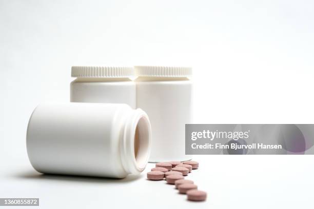 three neutral white pill boxes. one lying open with pills on the outside isolated against white background. neutral pink pills in front of the boxes - finn bjurvoll stock pictures, royalty-free photos & images