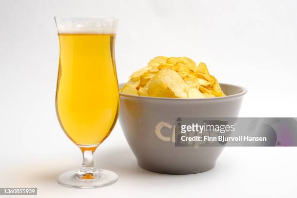 gray bowl with potato chips and a glass of light beer. isolated against a white background - finn bjurvoll stock pictures, royalty-free photos & images