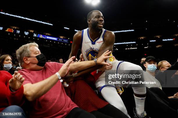 Draymond Green of the Golden State Warriors falls into the crowd attempting to save an out-of-bounds ball during the first half of NBA game against...