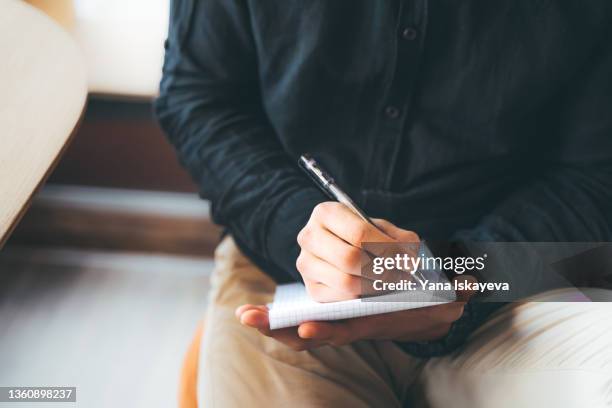 young asian man is making handwritten notes in a notepad - copyright stock pictures, royalty-free photos & images