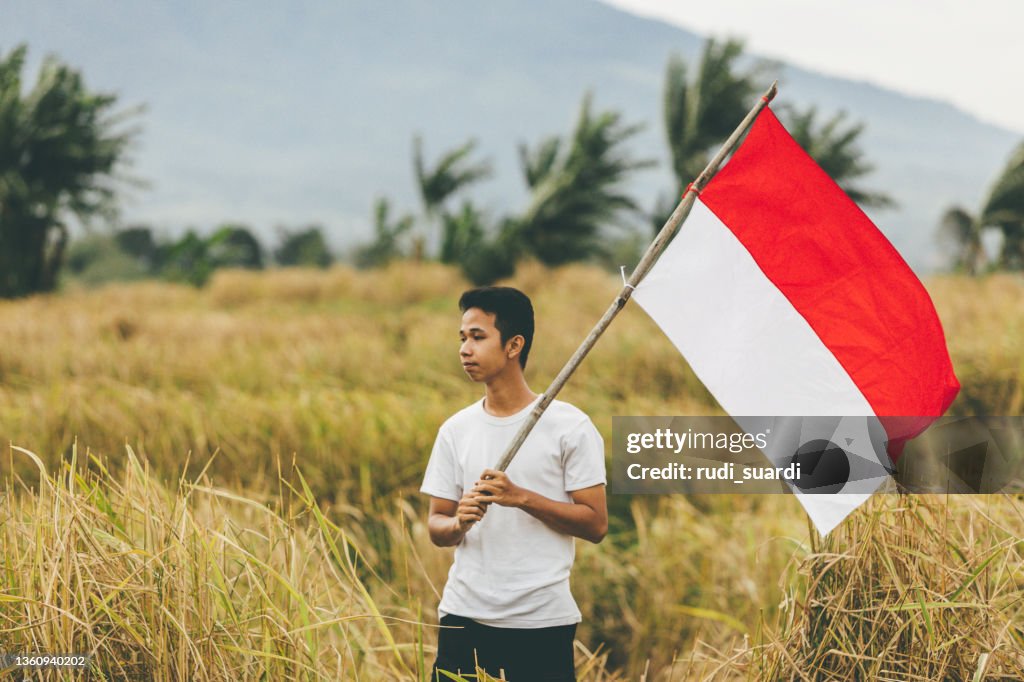 Jeune adulte asiatique tenant le drapeau de l’Indonésie dans le village