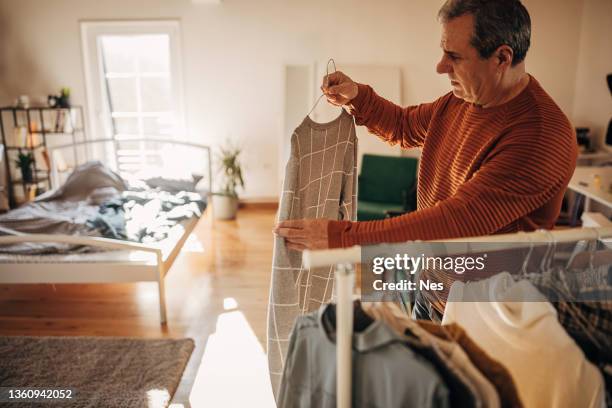 un hombre elige ropa en casa - un solo hombre mayor camisa fotografías e imágenes de stock