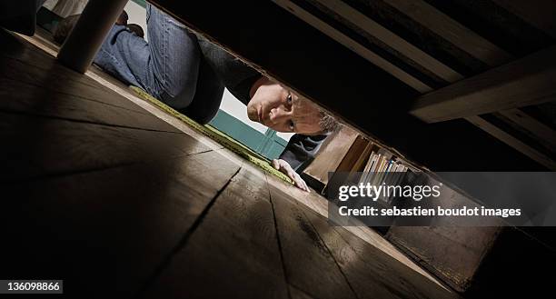 man looking under bed - mirar abajo fotografías e imágenes de stock