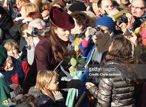 Catherine, Duchess of Cambridge accepts flowers from members of the crowd as she leaves Sandringham Church after the traditional Christmas Day...