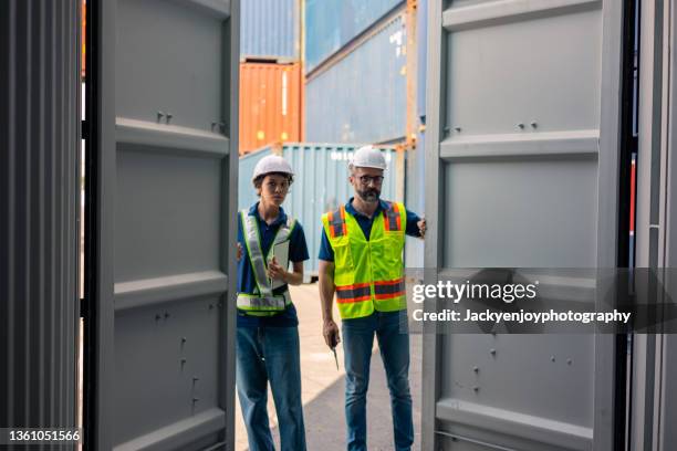 male port worker opening empty shipping container - open shipping container stock pictures, royalty-free photos & images