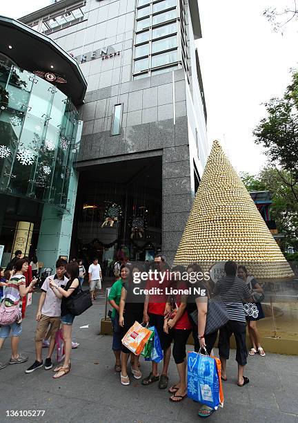 People pose with a christmas tree made up of Ferrero Rocher chocolates at a Orchard Road shopping mall at The Heeren on December 25, 2011 in...