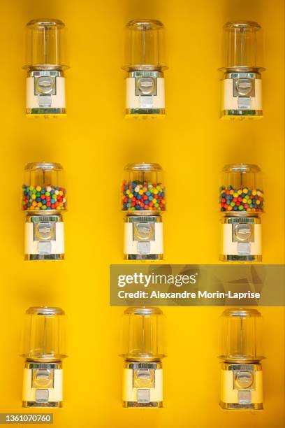 gumball vending machines against a yellow wall - dispenser foto e immagini stock