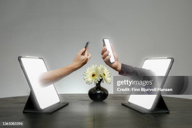 online dating. hands come out of a pad where both hands are holding their smartphones - finn bjurvoll stock pictures, royalty-free photos & images