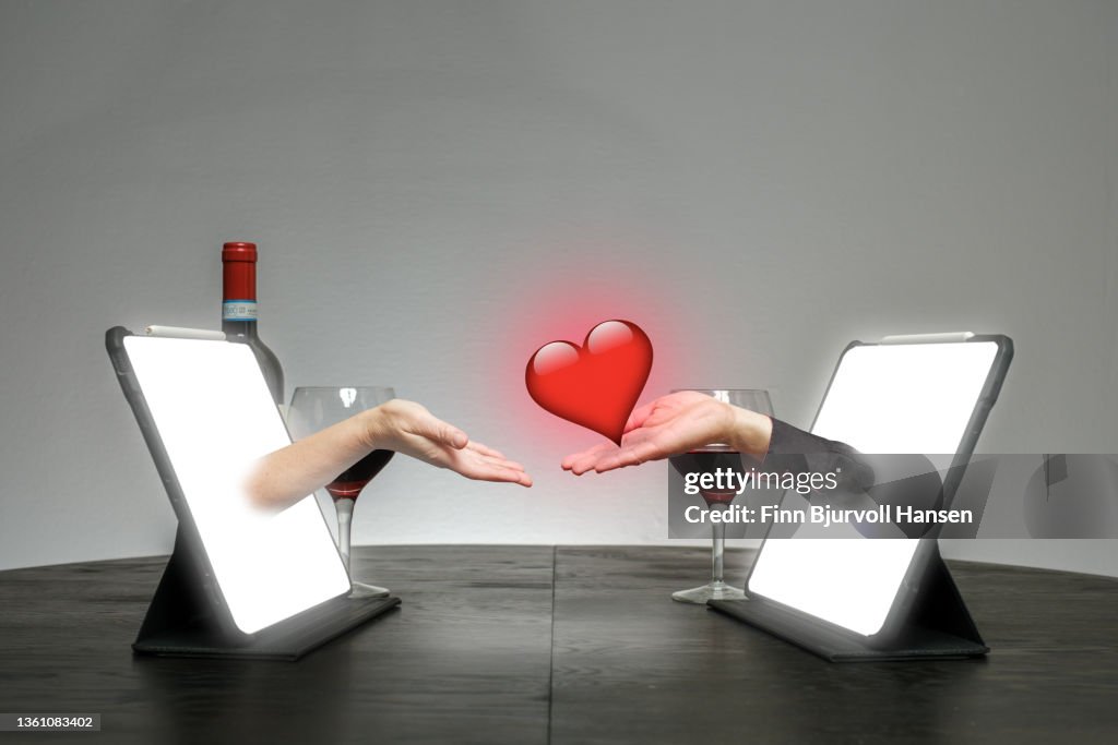 Online dating. Hands come out of a pad on a table where one hand gives a heart to the other