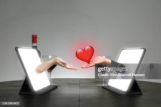 online dating. hands come out of a pad on a table where one hand gives a heart to the other - finn bjurvoll stock pictures, royalty-free photos & images