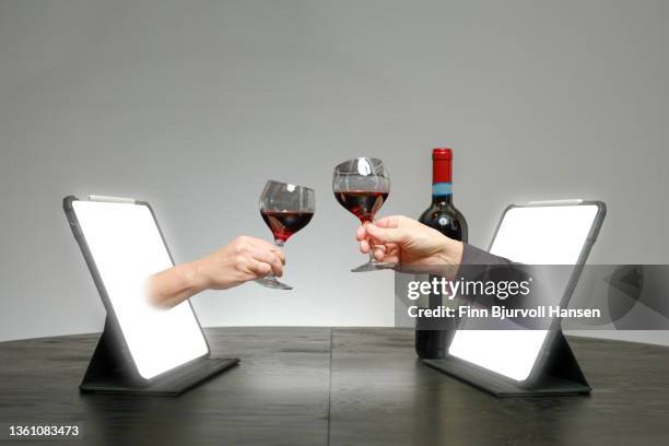 online dating. hands come out of a pad on a table where they toast with red wine - finn bjurvoll stock pictures, royalty-free photos & images