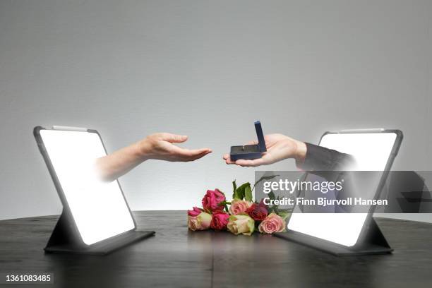 online dating. hands come out of a pad on a table where one hand holds a box with a ring. online proposal. - finn bjurvoll stock pictures, royalty-free photos & images