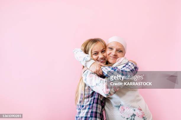 a woman with cancer is next to her daughter. a girl is hugging a woman happy - cancer patient with family stock pictures, royalty-free photos & images