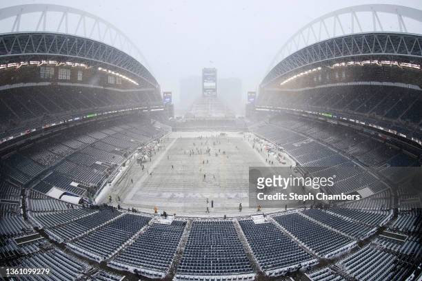 Field staff work on clearing the snow at Lumen Field before the game between the Seattle Seahawks and Chicago Bears on December 26, 2021 in Seattle,...