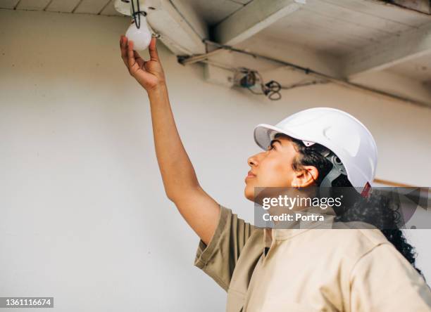 woman electrician installing a fluorescent light bulb - overdracht business mensen stockfoto's en -beelden