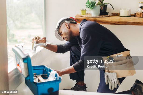 plumber fixing a leaking bathroom faucet - fixing stock pictures, royalty-free photos & images