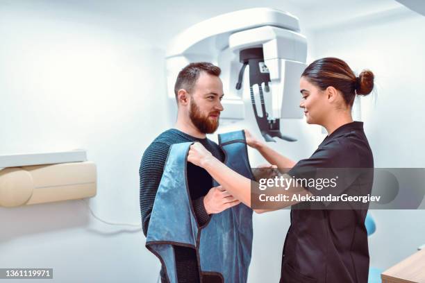 female dental radiologist preparing male patient for dental computer tomography - vest stock pictures, royalty-free photos & images