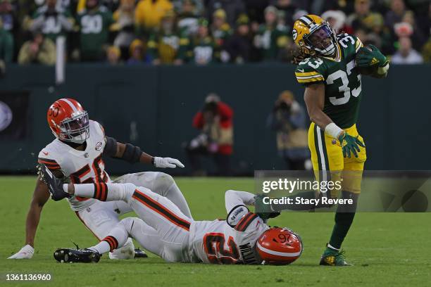 Aaron Jones of the Green Bay Packers s tripped up by Greedy Williams of the Cleveland Browns during a game at Lambeau Field on December 25, 2021 in...