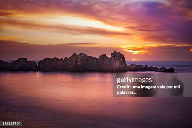 rock in sea with sunset in background - fotografia imagem fotografías e imágenes de stock