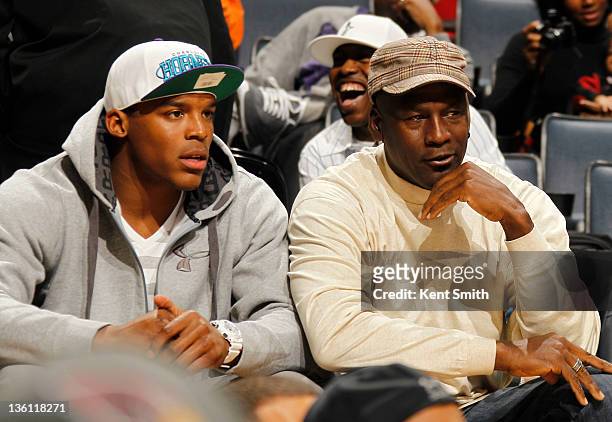 Quarterback Cam Newton of the Carolina Panthers and Charlotte Bobcats owner Michael Jordan sit courtside during the season opener against the...
