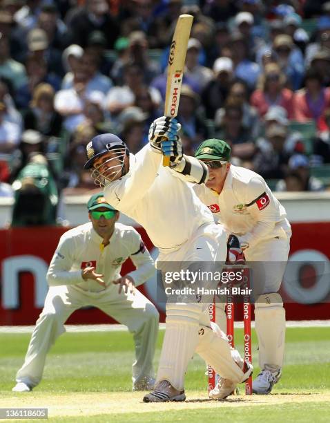 Virender Sehwag of India drives with Michael Clarke and Brad Haddin of Australia looking on during day two of the First Test match between Australia...