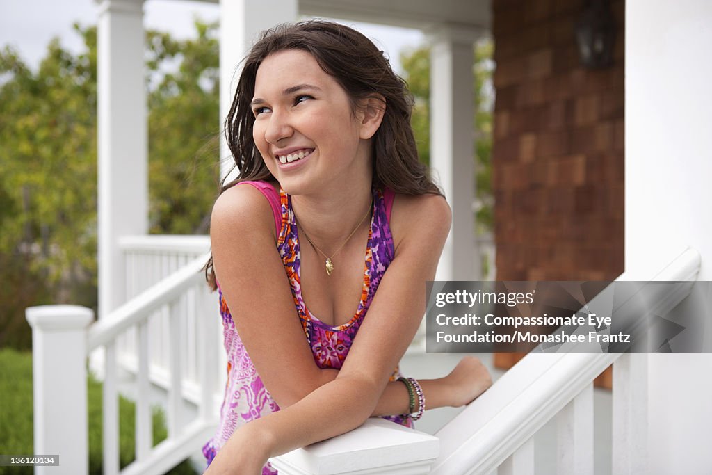 Teenage girl (14-15) on porch, portrait, smiling