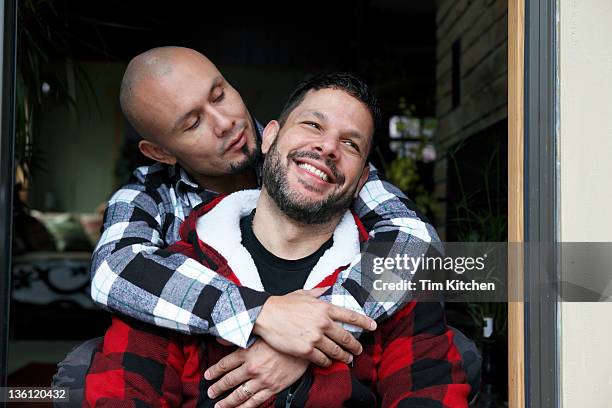 handsome latin couple in doorway of house, candid - gay couple in love stock pictures, royalty-free photos & images