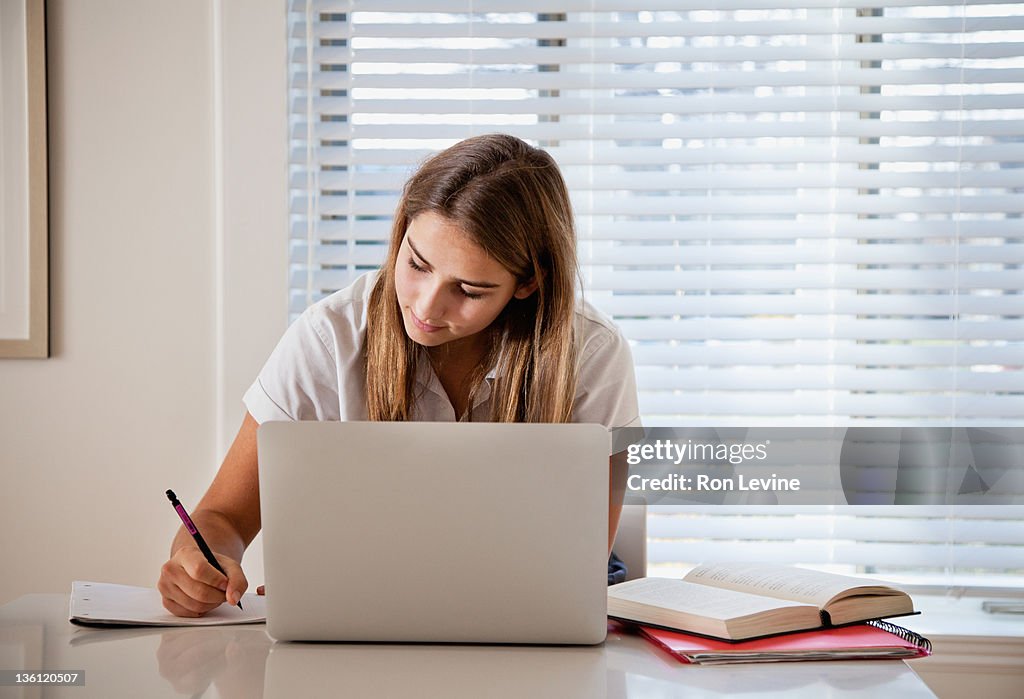 Teen girl doing homework in kitchen