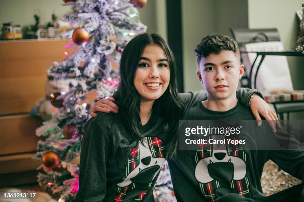 portrait of cheerful sibling posing in pajamas in front of the xmas tree in xmas morning - 12 days of christmas fotografías e imágenes de stock