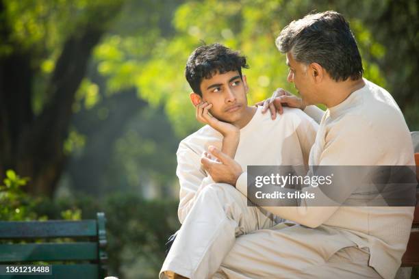 padre consolando a su hijo en el parque - boy sad fotografías e imágenes de stock