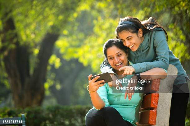 mother and daughter laughing while using mobile phone - asian mother daughter stock pictures, royalty-free photos & images