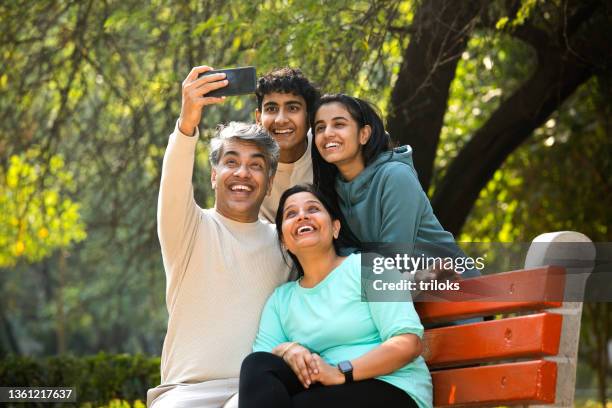 happy family taking selfie using mobile phone camera - indian family in their 40's with kids imagens e fotografias de stock