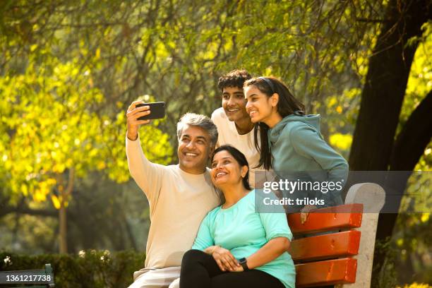 happy family taking selfie using mobile phone camera - indian family in their 40's with kids imagens e fotografias de stock