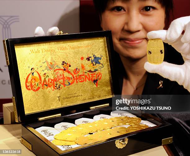 An employee of Tanaka Kikinzoku Jewelry displays a pure gold made oval coin designed with Mickey Mouse and Walt Disney on its surface for the...