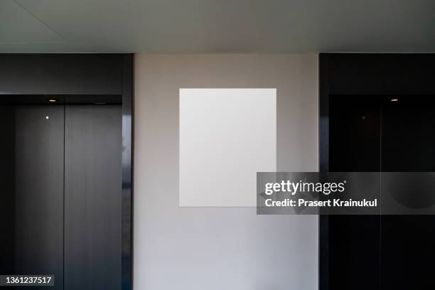 realistic elevators with close doors and blank white ad poster screen on wall - poster stockfoto's en -beelden