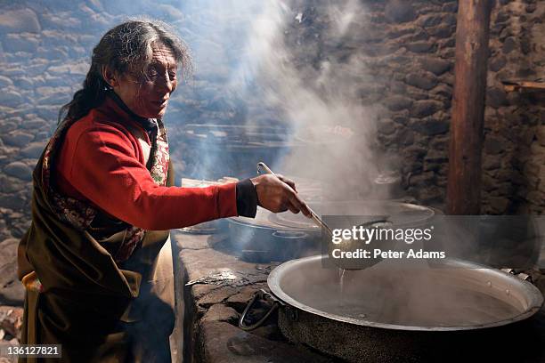 tibetan man with pan of boiling water in kitchen - chinese cauldron stock pictures, royalty-free photos & images