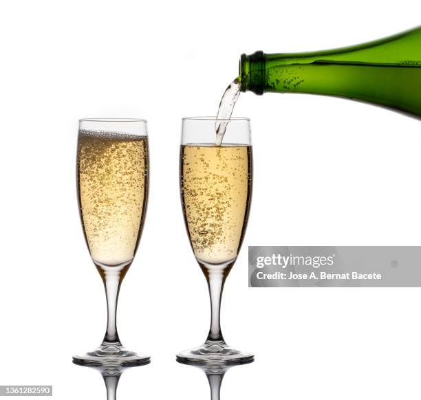 bottle filling two glasses of champagne on a white background. - champagner gläser mit flasche unscharfer hintergrund stock-fotos und bilder