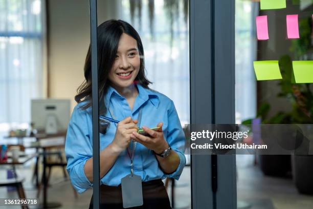 young female in the office glues sticky sheets on the glass partition of the office of a large company. - developers scrum stock pictures, royalty-free photos & images