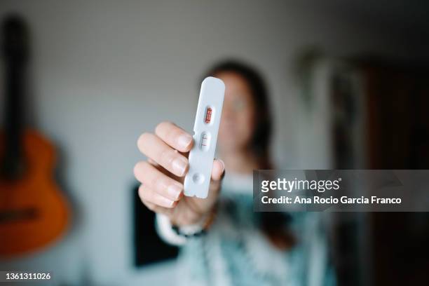 woman holding a positive rapid test - positive emotionen stock-fotos und bilder