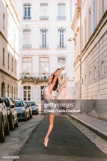 female ballet dancer dancing alone in the street wearing a dress and pointes - cocktail dress stock pictures, royalty-free photos & images