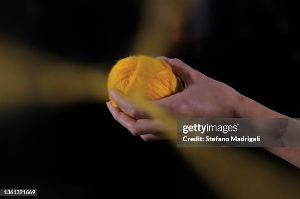 yellow ball of yarn in hand with thread hanging - wool ball foto e immagini stock