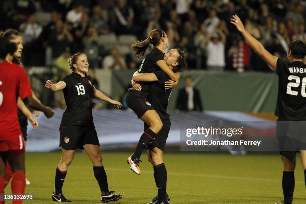 Alex Morgan of the United States is hoisted by teammate Lauren Cheney after scoing a goal against Canada on September 22, 2011 at Jeld-Wen Field in...