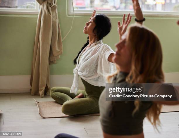 frau meditiert mit erhobenen armen während eines yoga-kurses - chakras stock-fotos und bilder