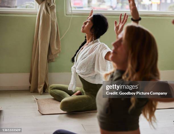 woman meditating with raised arms during a yoga class - chakras stock pictures, royalty-free photos & images