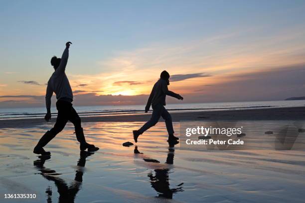 couple using stepping stones on beach - 踏み石 ストックフォトと画像