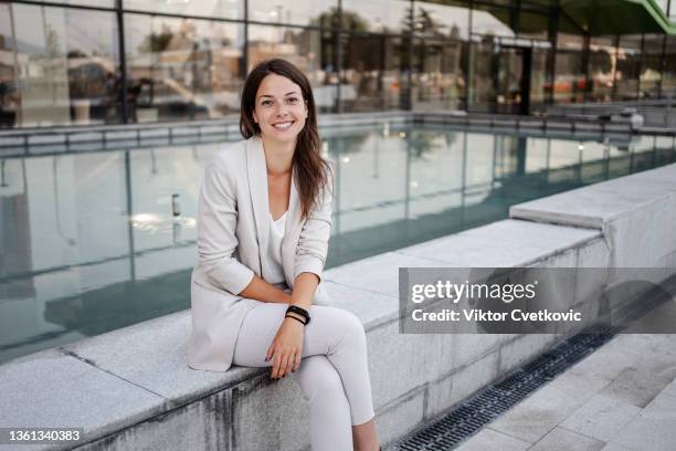 portrait of a beautiful white business woman sitting near the fountain - werkneemster stockfoto's en -beelden