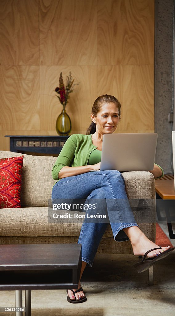 Mid-aduklt woman using her laptop on the couch
