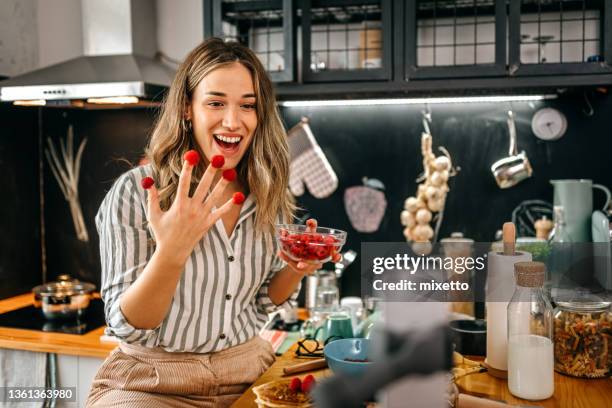 women food blogger with raspberries on fingers recording vlog - juicy raspberry stock pictures, royalty-free photos & images