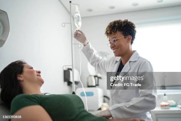 doctor talking with a patient and taking iv drip at a medical clinic - iv drip stockfoto's en -beelden